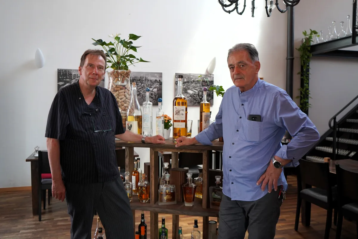 Man sieht zwei Männer vor einer Auslage mit Schnaps.